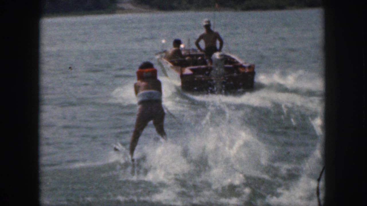 1961 Michigan 8mm frame showing a life-vested water skier being towed by a motorboat on a tree-lined lake.