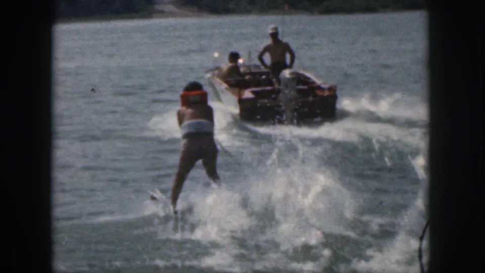 1961 Michigan 8mm frame showing a life-vested water skier being towed by a motorboat on a tree-lined lake.