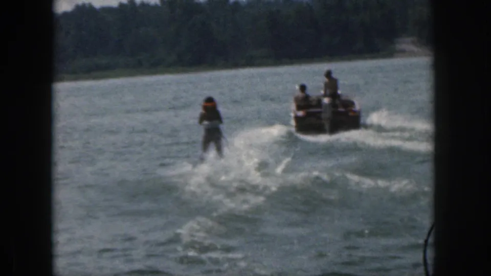 1961 Michigan 8mm frame showing a distant water skier following a boat across a calm lake.