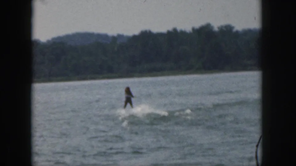 1961 Michigan lake scene with a water skier centered in the frame, partly softened by 8mm motion blur and distance.