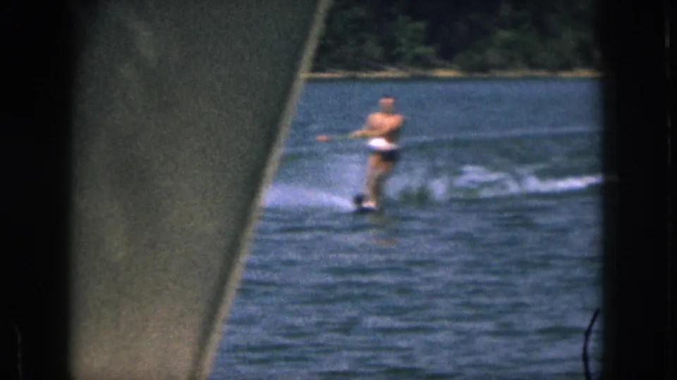 1961 Michigan 8mm frame with a water skier on the lake, partly framed by a dark foreground edge and film border.