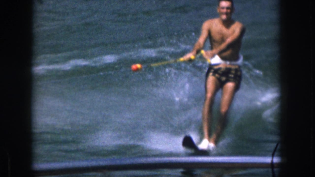Close view of a man water skiing through spray on a lake.