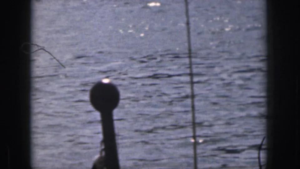 1961 Michigan home-movie frame showing rippled lake water after the skier has moved out of view, with dark frame edges and scan artifacts.