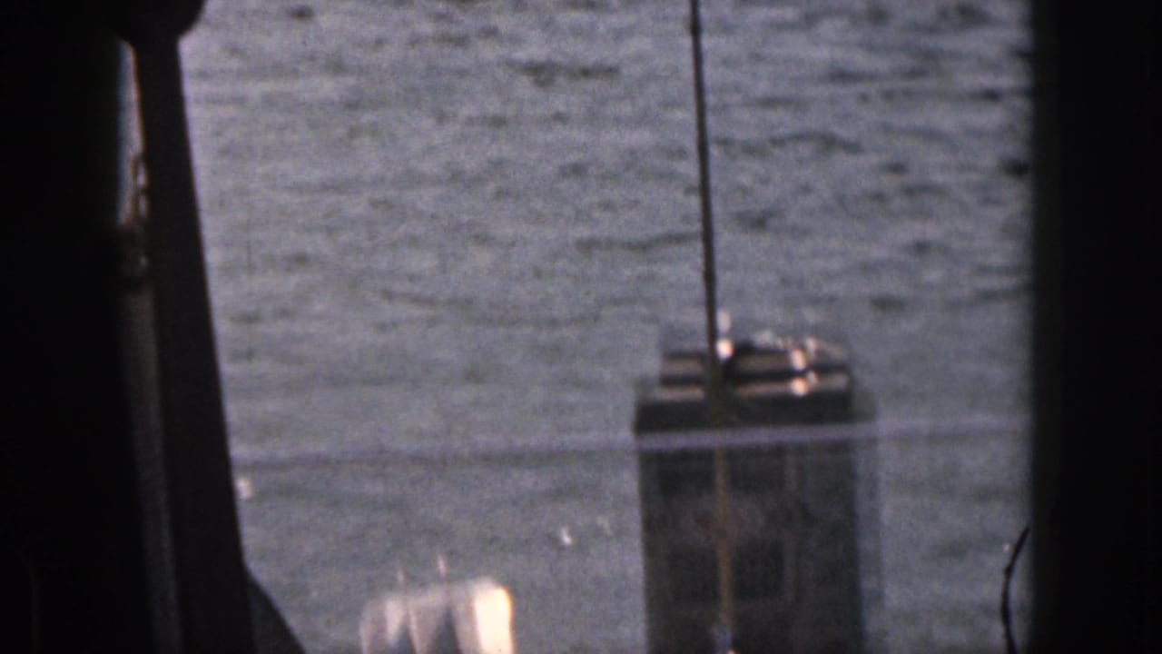 Open water with dark vertical framing and a small structure or boat detail at right.