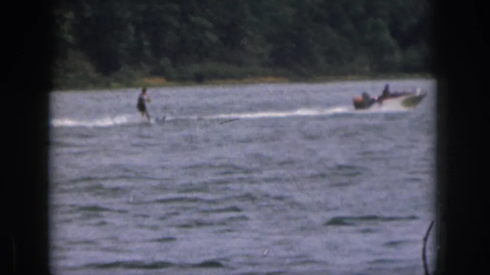 1961 Michigan lake scene with a water skier trailing a small motorboat across sunlit water.