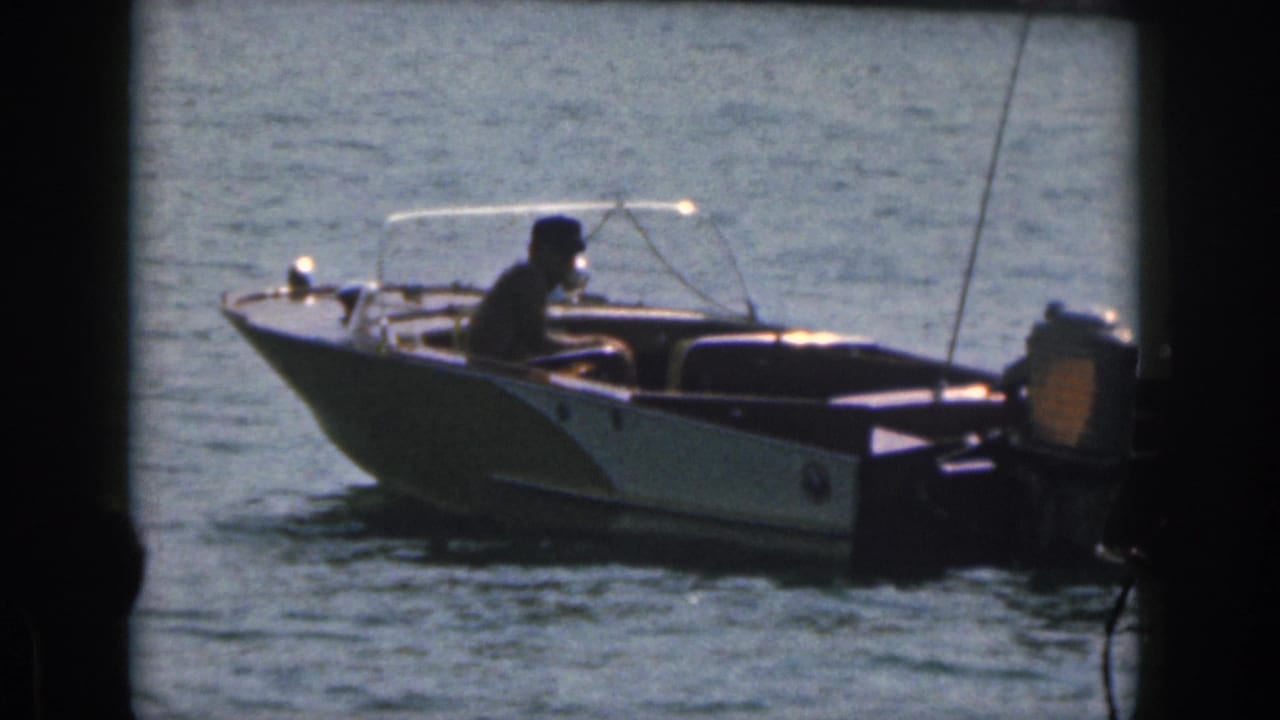 Small motorboat with one operator moving across sunlit water.
