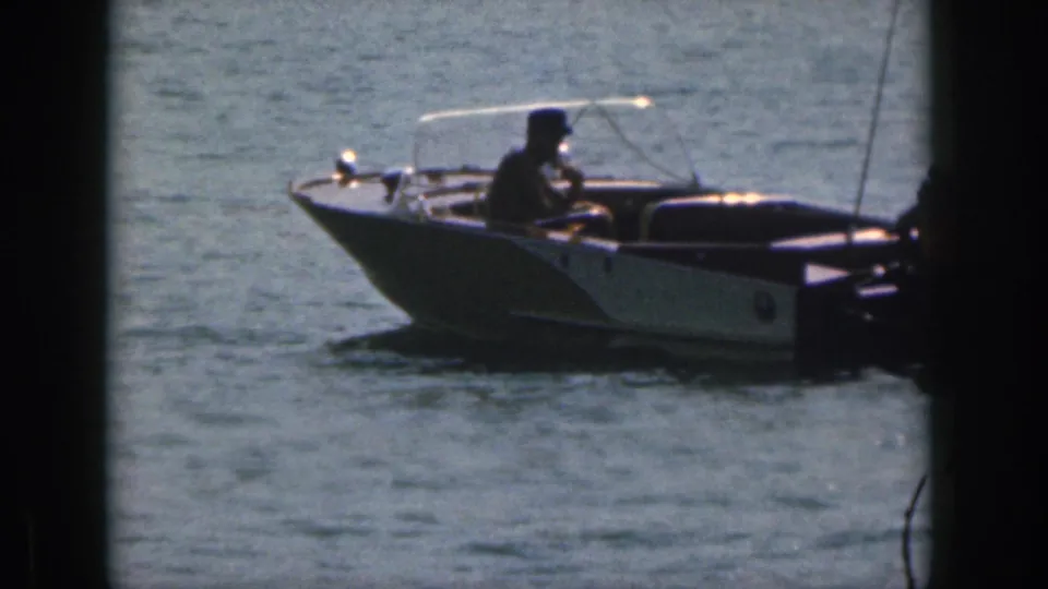 A 1961 Michigan boating frame shows one man at the helm of a small motorboat, partly near the film-frame border.