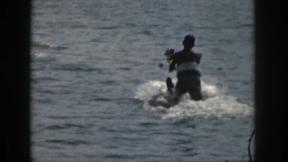 1961 Michigan lake footage showing a person starting to water ski with white spray behind the skier.