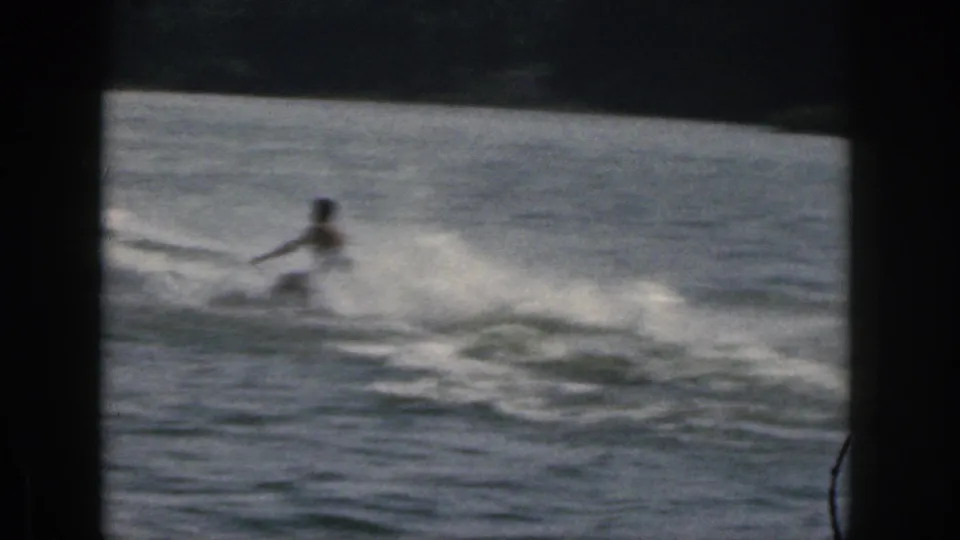 1961 Michigan 8mm frame showing the water skier losing balance or falling, with a broad spray trail across the lake.