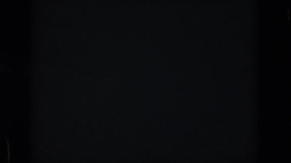 Blank or obscured opening frame from the 8mm clip, showing dark exposure and minimal visible detail before the lake scene appears.