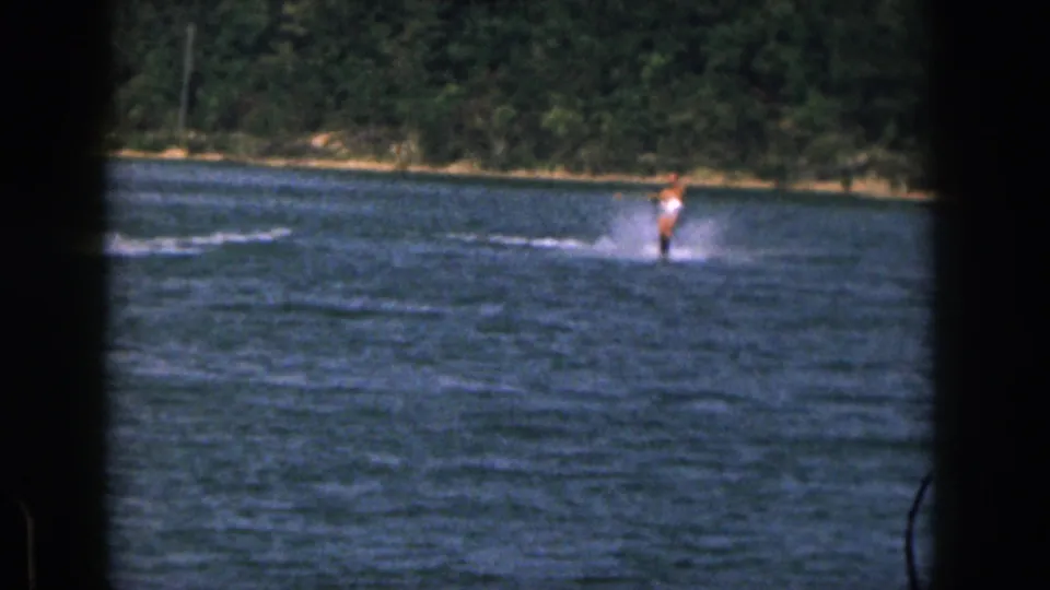 1961 Michigan frame with a shirtless skier in white shorts crossing the river while the tow boat is mostly out of view.