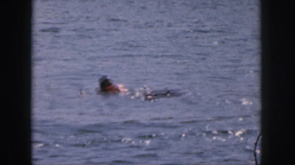 1961 Michigan 8mm frame showing a person in the lake near floating equipment after the water-skiing pass.