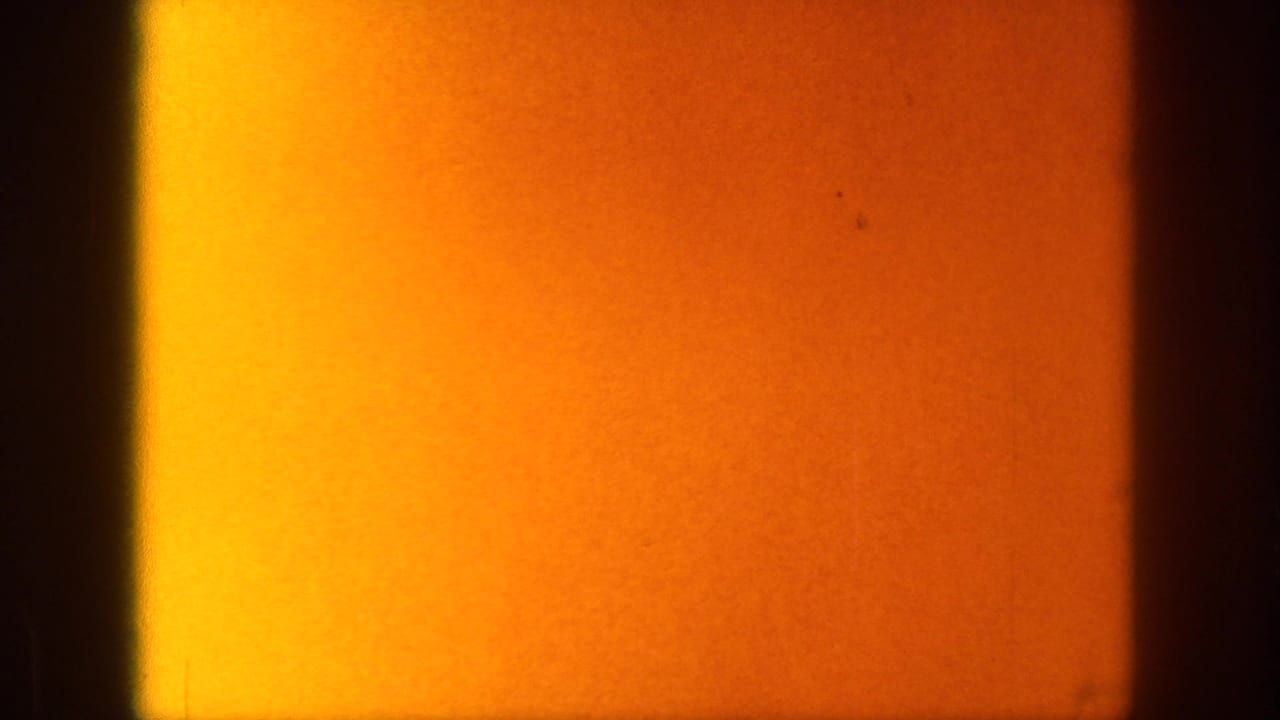 Warm orange film exposure and dark frame edge with little discernible subject detail.
