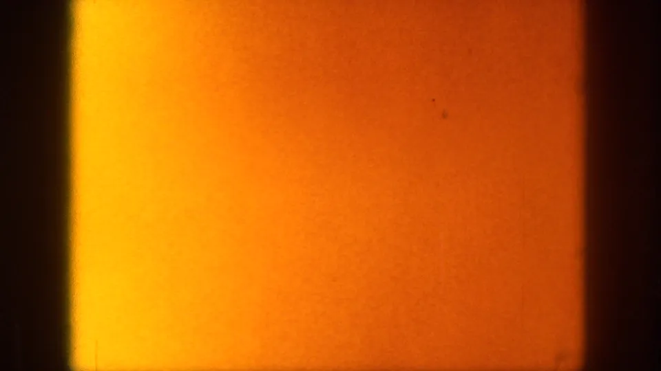 Warm orange 8mm exposure area from the 1961 Michigan home movie, with dark vertical frame edge and film texture visible.