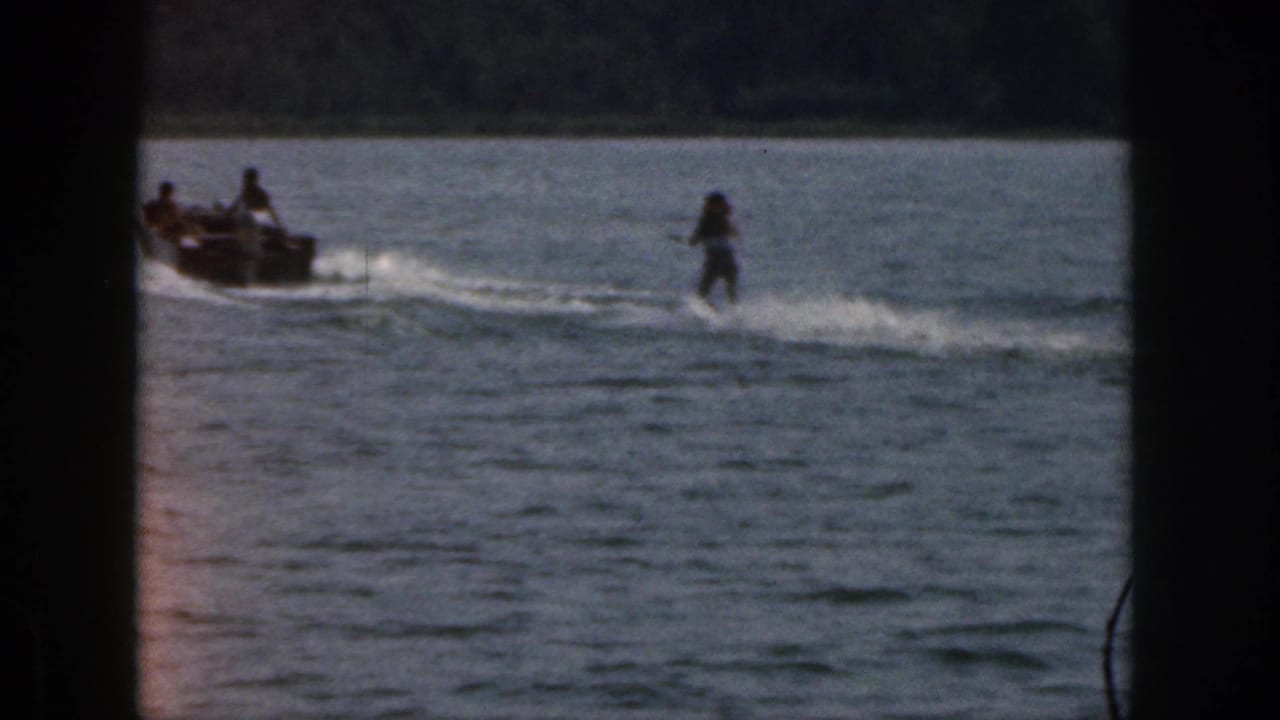 Motorboat towing a water skier across open lake water.