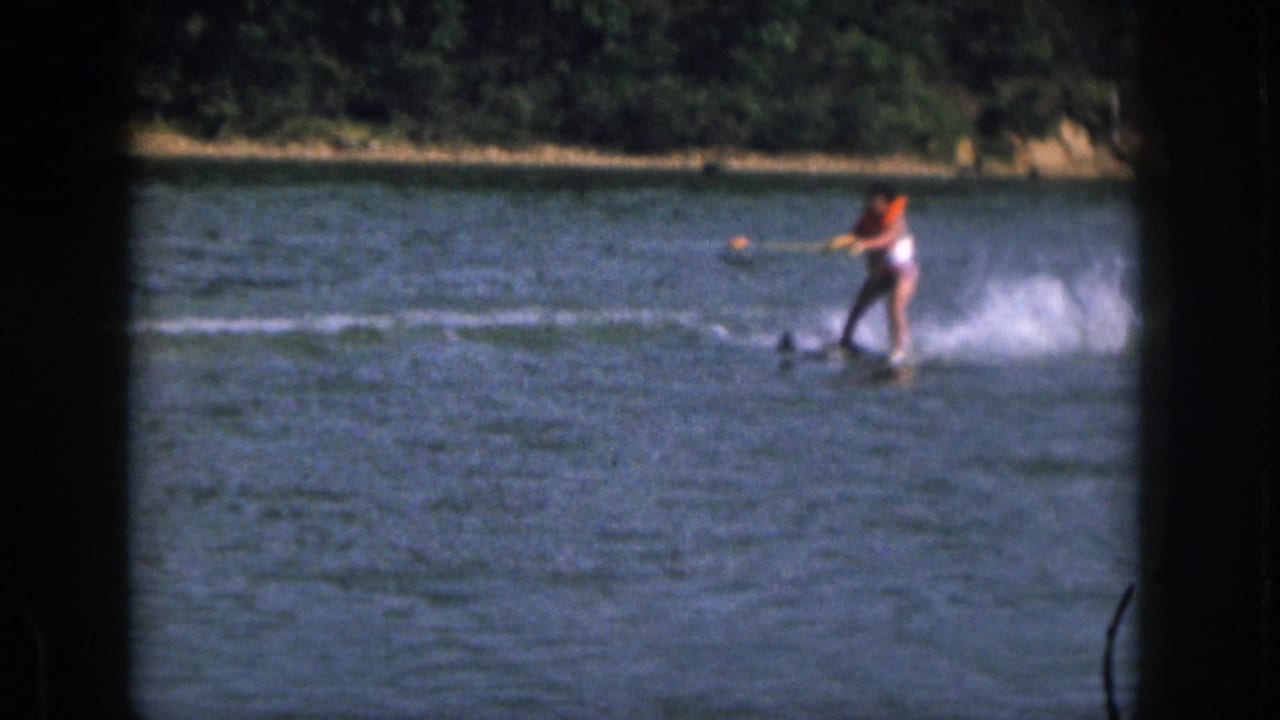 Water skier holding a tow rope while moving across blue lake water.