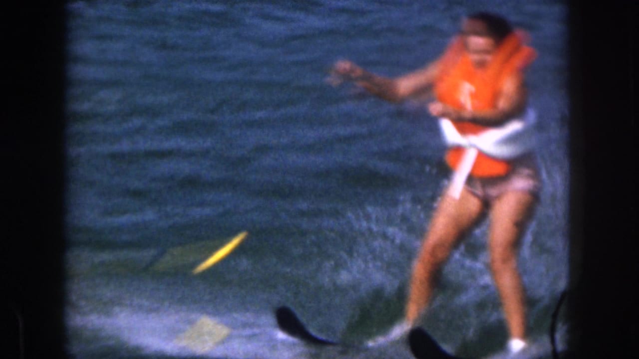 The woman appears to lose balance on water skis during the lake outing, with one ski lifting and water spray around her.