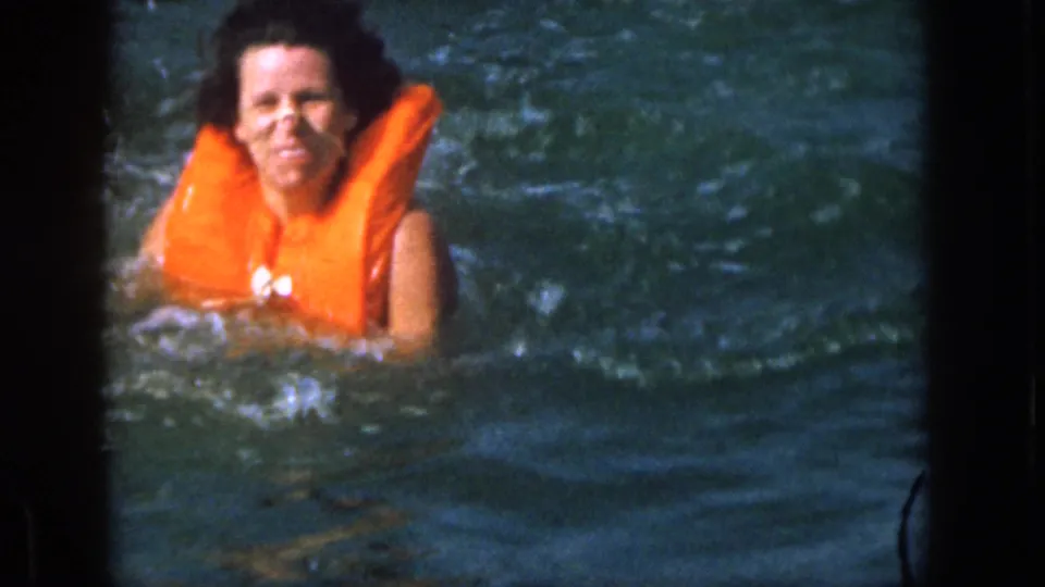 After the fall, the woman smiles from the lake water in the supplied 1961 Michigan recreational home-movie footage.