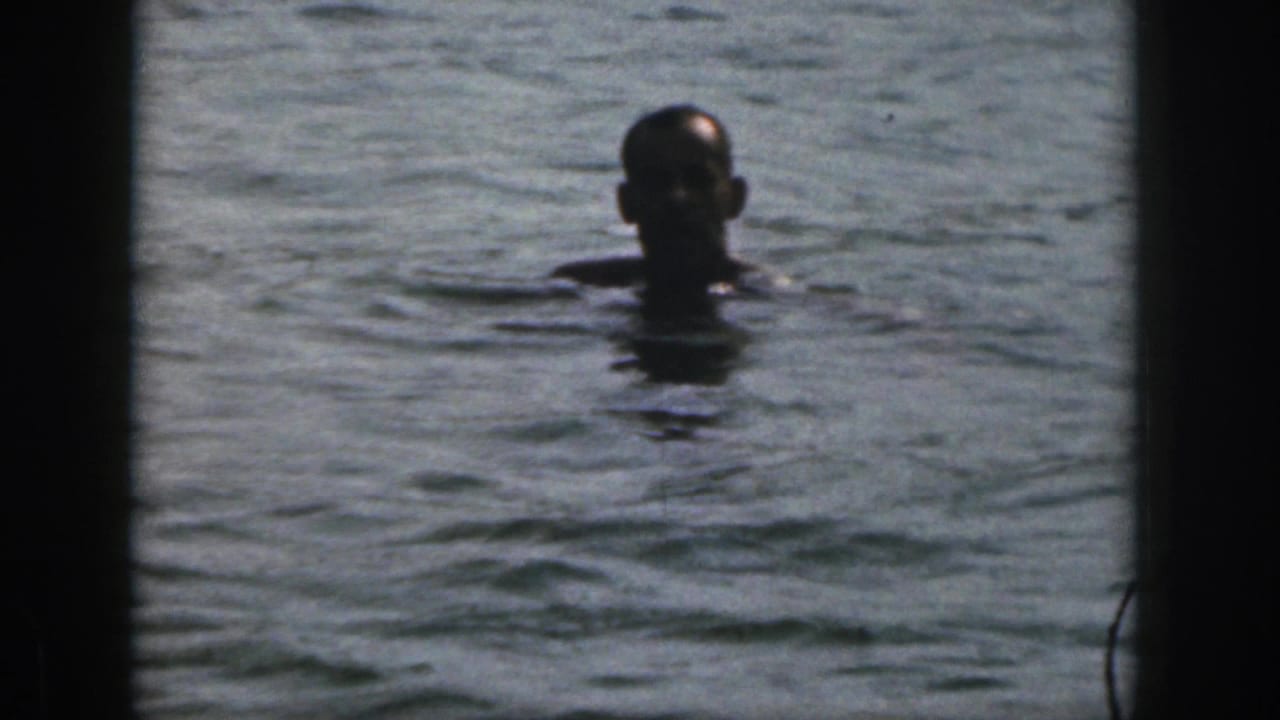 Man's head and shoulders visible above the river surface after entering the water.