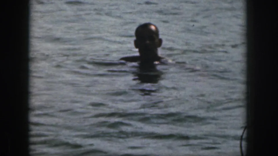 1961 Michigan home-movie frame showing the skier in the water, with his head and shoulders visible above the river surface.