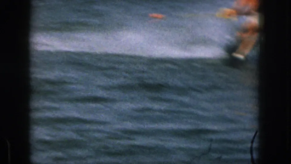Soft 8mm frame from the Michigan lake scene with the water skier partly blurred near the edge and spray across the water.