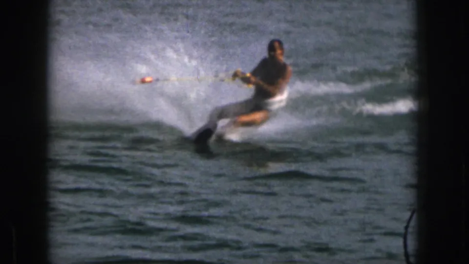 During the slalom maneuver, the man appears to lose control, with his body low over the lake and a large spray of water surrounding the ski.