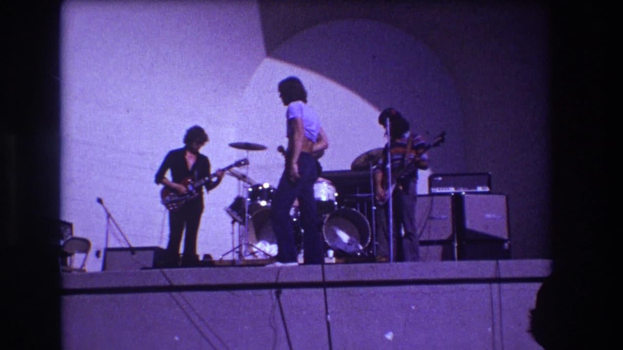 Closer 1973 Medford concert frame with guitarist, lead singer, drummer, and bassist on an outdoor stage.