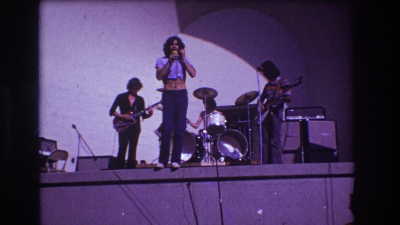 Four musicians appear on a simple stage in the supplied 1973 Medford footage, with the singer centered and band members playing around him.