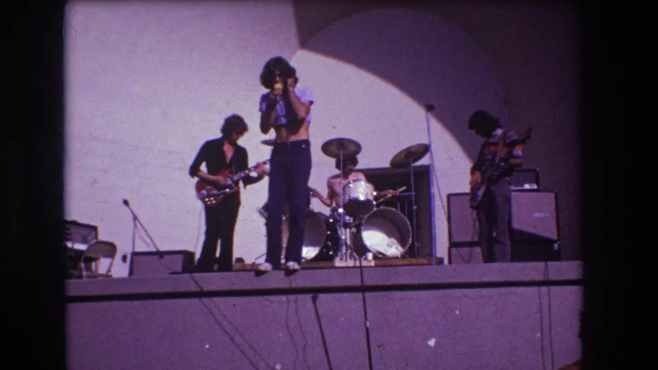 1973 Medford, New Jersey frame with the singer near center, guitarist and bassist at the sides, and drummer behind a white kit.