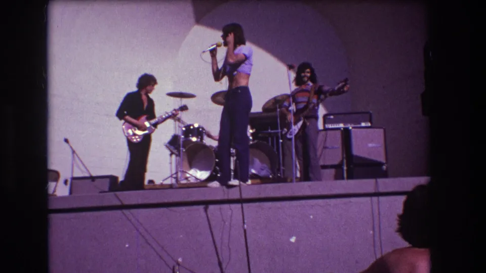 Medford, New Jersey 1973 8mm frame of the band performing, with the singer in profile and musicians arranged across the stage.
