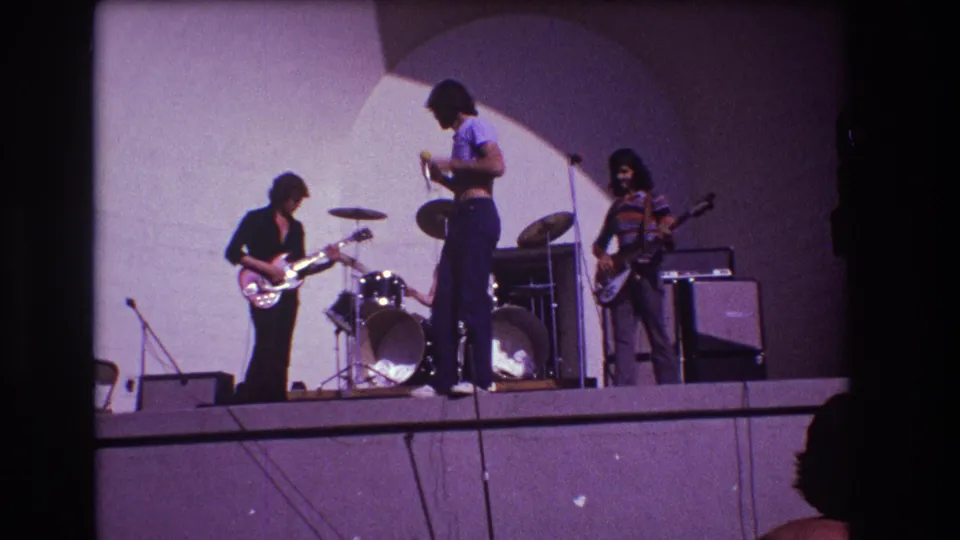 1973 Medford, New Jersey stage view with vocalist, guitarist, bassist, drum kit, and amplifiers during a pre-show warmup.