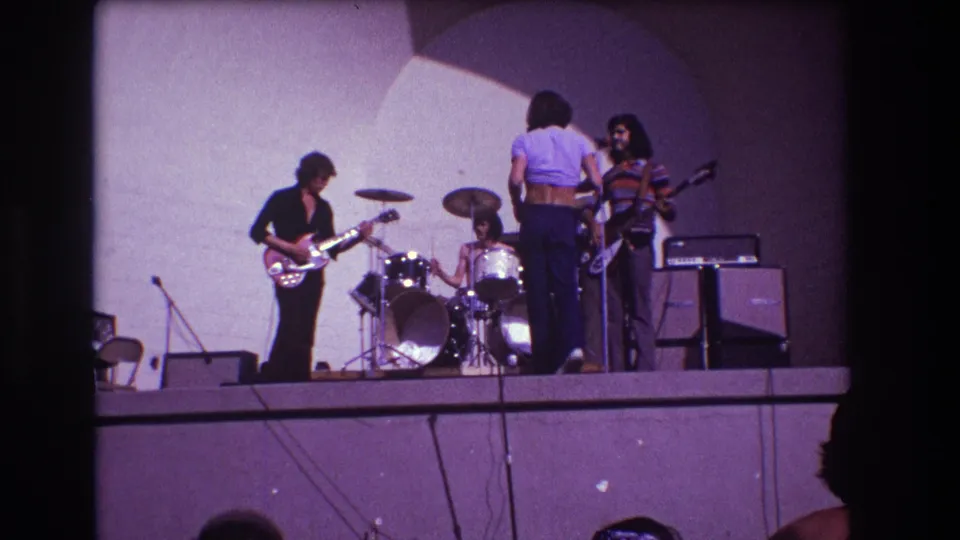 1973 Medford, New Jersey frame with drummer centered behind the kit and bandmates gathered during stage setup.
