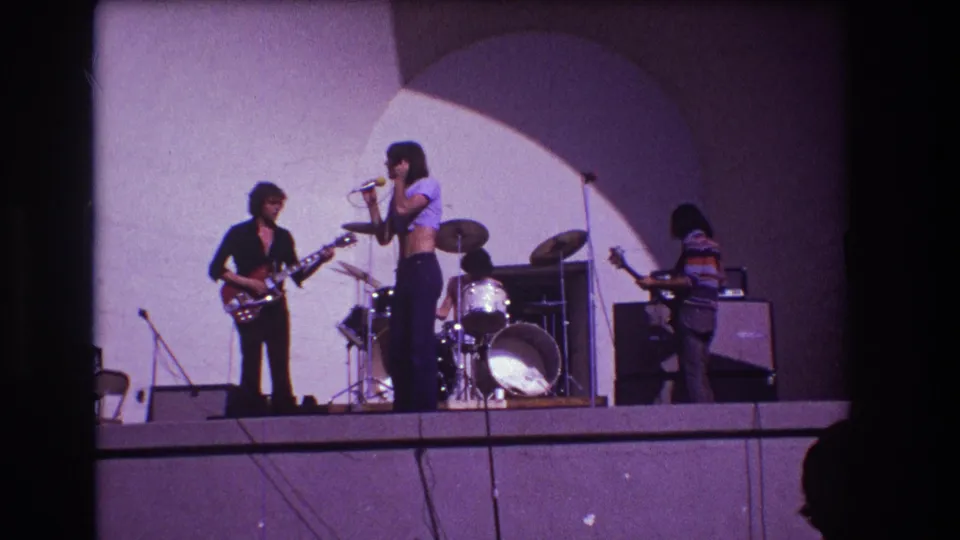 1973 Medford, New Jersey concert frame with singer at center, guitarist at left, drummer behind, and bassist near amplifiers.