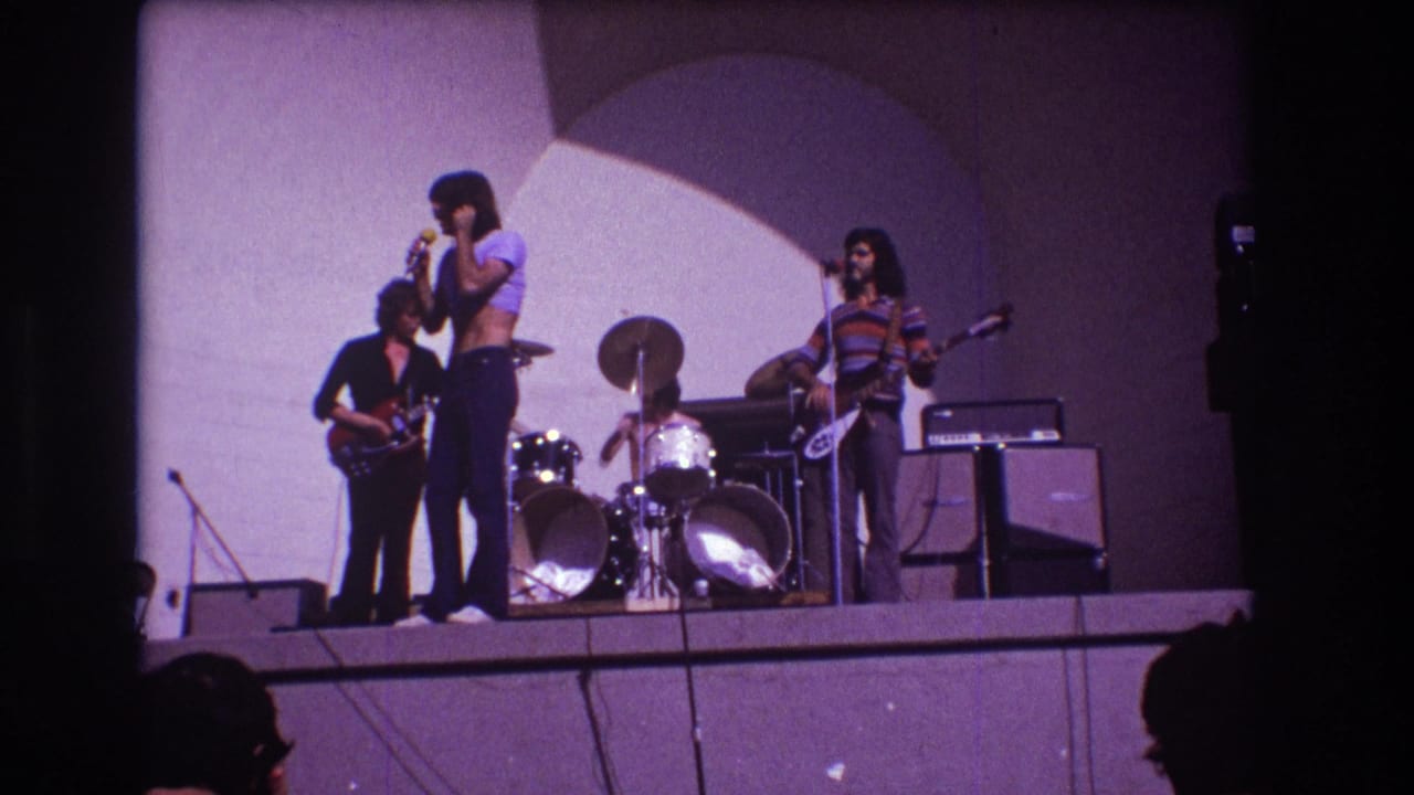 Four-piece rock band performing on a stage with singer, guitarist, drummer, and bassist.