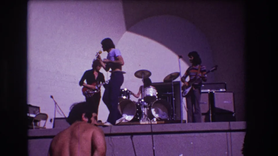 1973 Medford, New Jersey frame with the singer moving across the raised stage as guitarists and drummer continue the performance.