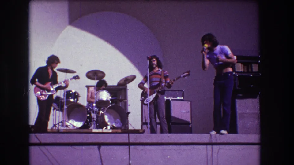 1973 Medford 8mm frame showing the singer near the right edge with guitar, bass, and drums across the stage.