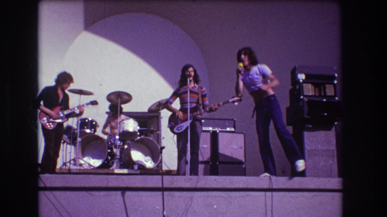 The 1973 Medford stage performance shows the lead singer leaning forward with a microphone as guitarist, drummer, and bassist continue playing.