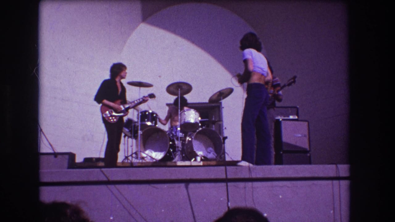 1973 Medford, New Jersey concert frame with the singer turned partly away from camera as the guitarist and drummer continue on stage.