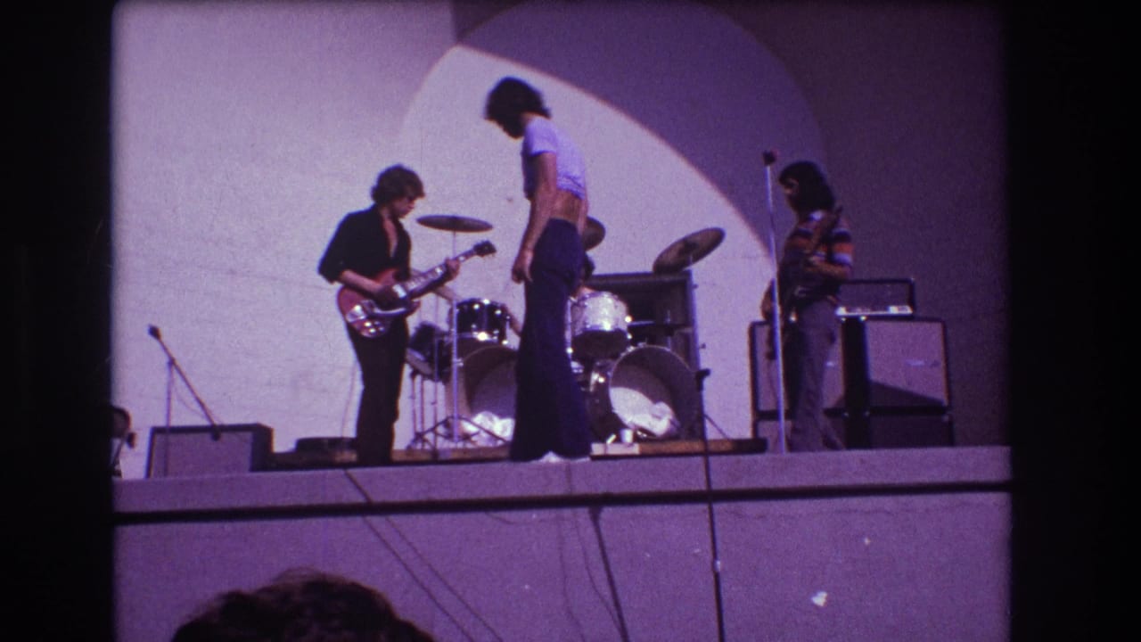 Vocalist stands near center stage while guitarist, drummer, and right-side musician continue playing.