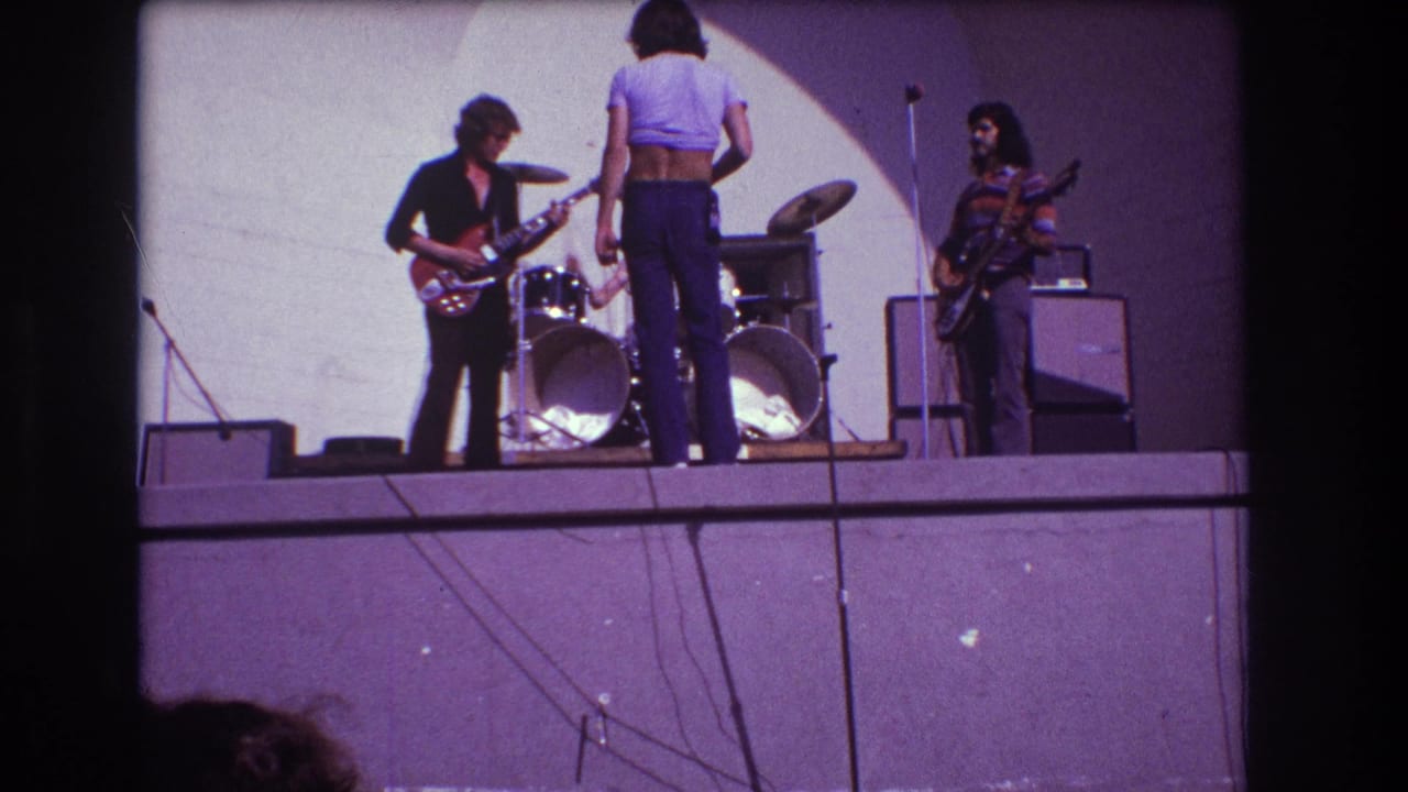 1973 Medford, New Jersey frame with guitarists, a front performer, and a drummer gathered around a drum kit during rehearsal.