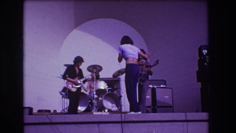 1973 Medford, New Jersey 8mm frame showing the singer from behind while the rock band performs with drums, guitar, bass, and amps.