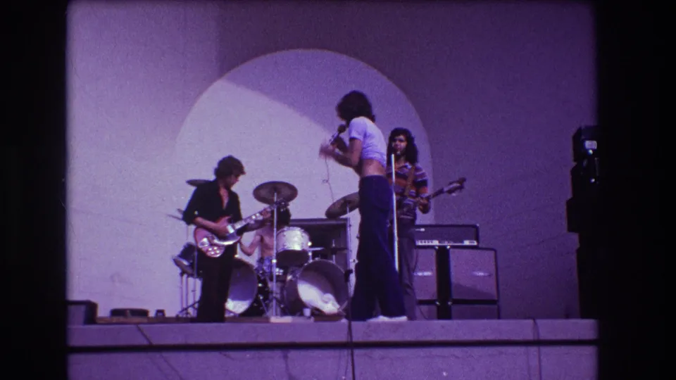 1973 Medford, New Jersey frame of a rock band performing, with singer at a microphone and musicians playing guitar, drums, and bass.