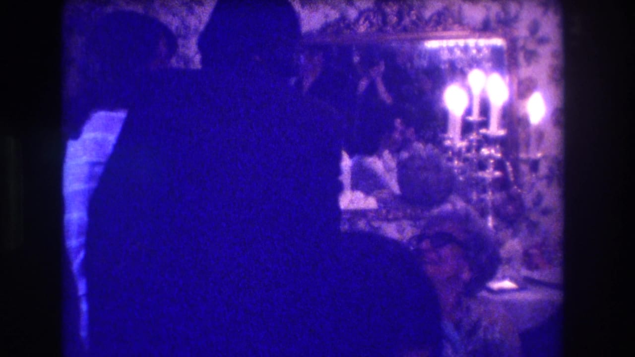 Two silhouetted figures appear to converse in the Medford, New Jersey interior, with a bright candelabra and patterned wall behind them.
