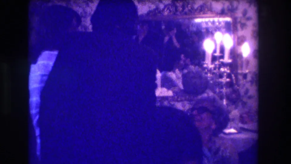 Two silhouetted figures appear to converse in the Medford, New Jersey interior, with a bright candelabra and patterned wall behind them.