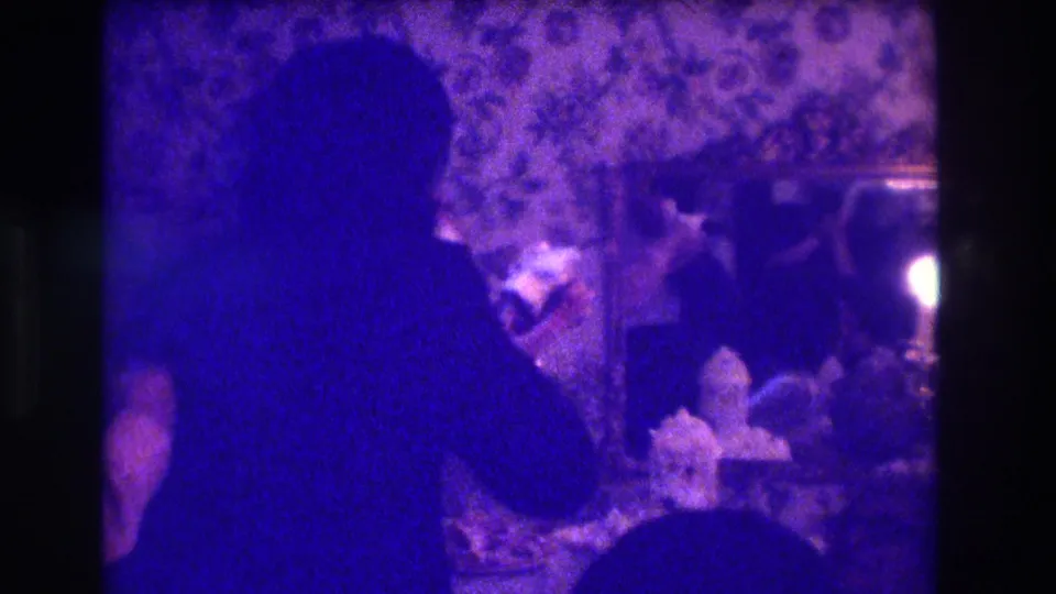 1973 Medford frame showing a dancer from behind during an indoor hula-style performance with candlelight and viewers.
