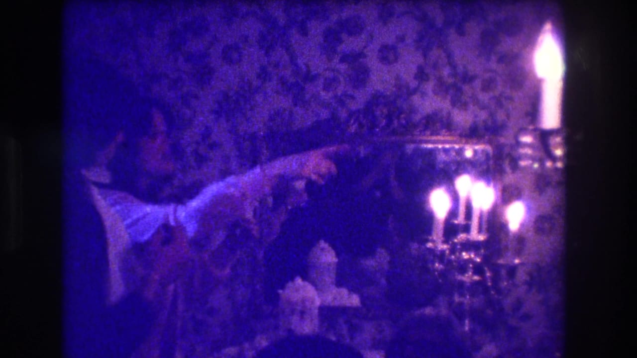 Dim indoor celebration with a person pointing near a cake, mirror, patterned wall, and bright candelabra.
