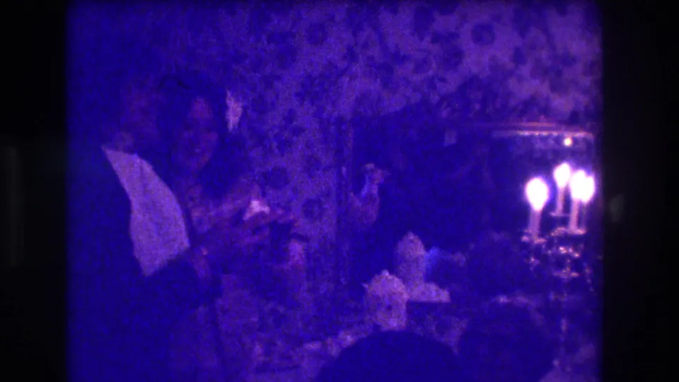 1973 Medford, New Jersey 8mm frame with a man in dark formalwear near other guests, candles, and ornate wallpaper.
