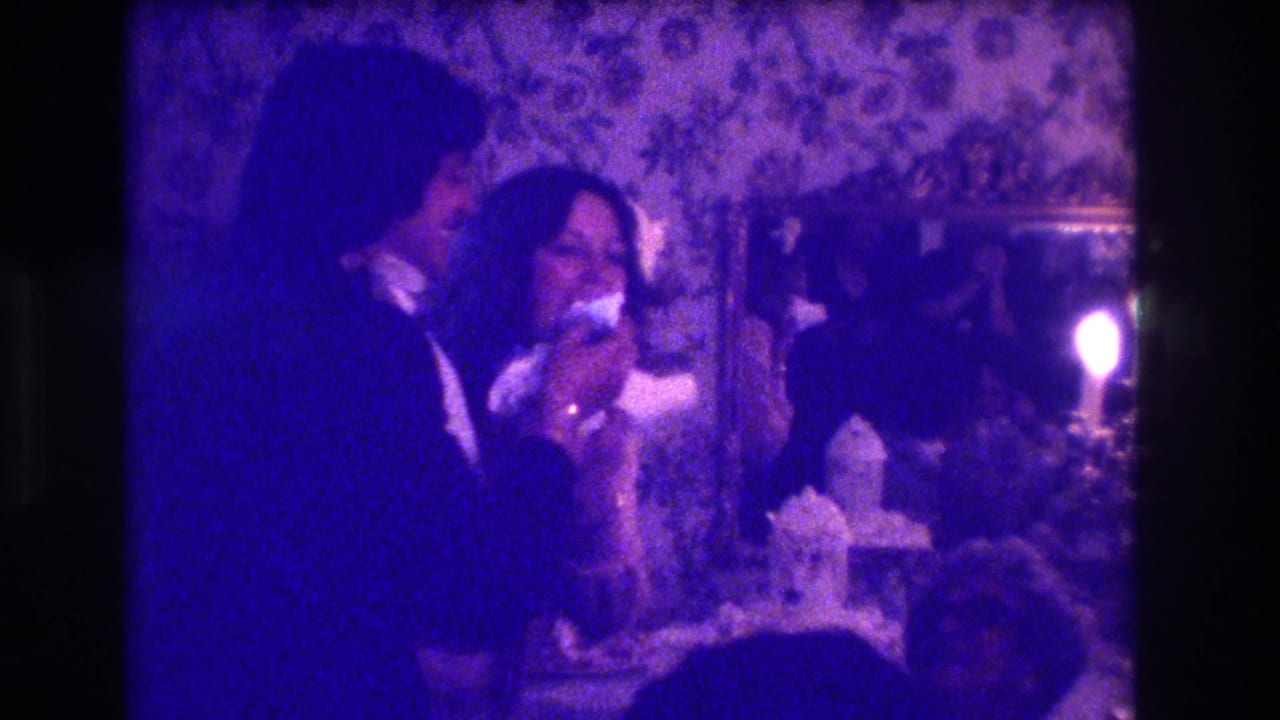 1973 Medford, New Jersey home-movie frame showing a bride and groom by the cake table in a purple-tinted reception interior.