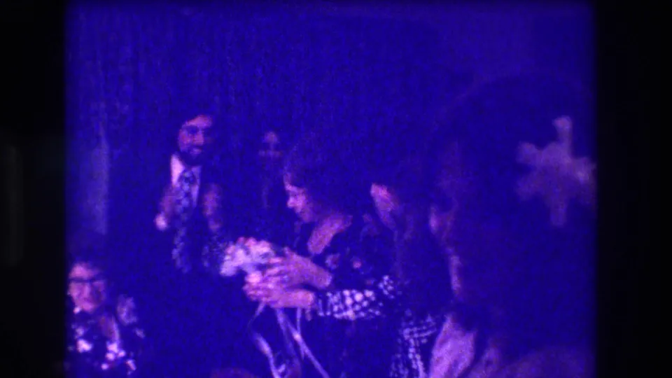 At the 1973 Medford wedding reception, a woman appears to hold the bouquet while guests in period formalwear gather nearby.