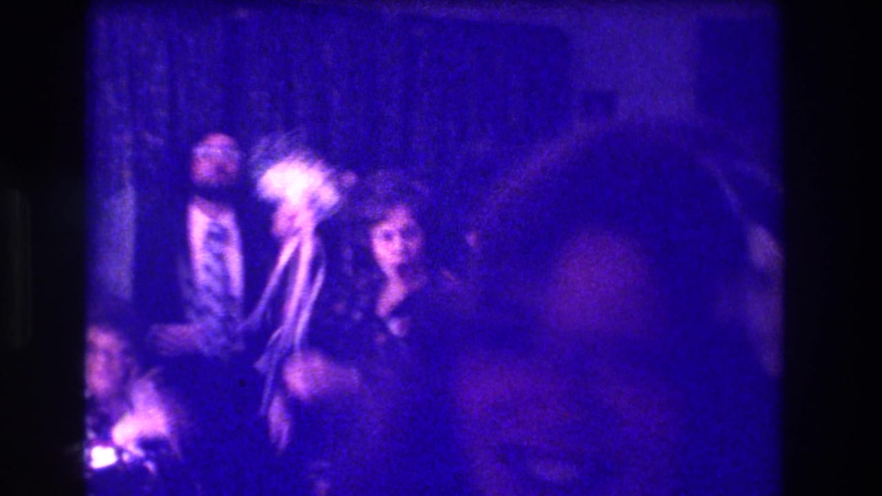Medford, New Jersey, 1973 home-movie frame showing adults in formal attire gathered in a crowded, blue-tinted interior.